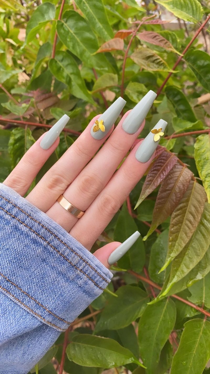 Пастельні шавлієво-зелені нігті з золотими наклейками-метеликами